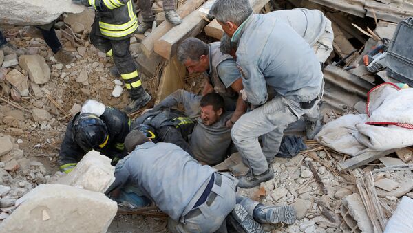 Спасатели помогают пострадавшему в землетрясении в городе Аккумоли в центральной Италии - Sputnik Кыргызстан