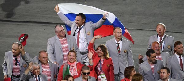 Директор Республиканского центра олимпийской подготовки по легкой атлетике, представитель белорусской делегации Андрей Фомочкин (на дальнем плане) с флагом России во время парада атлетов и членов национальных делегаций на церемонии открытия XV летних Паралимпийских игр 2016 в Рио-де-Жанейро. - Sputnik Кыргызстан