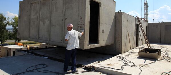 Рабочий контролирует установку бетонной конструкции на строительстве жилого дома. Архивное фото - Sputnik Кыргызстан
