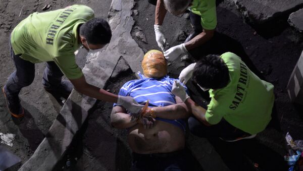 Сотрудники похоронной службы убирают клейкую ленту вокруг головы и запястья рук тела человека, которого полиция допрашивала в связи с наркотиками в Маниле, Филиппины. 21 сентября 2016 - Sputnik Кыргызстан
