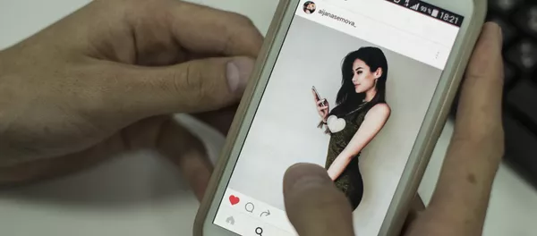 Пользователь смотрит страницу Instagram Айжан Асемовой с экрана смартфона Пользователь смотрит страницу Instagram Айжан Асемовой с экрана смартфона - Sputnik Кыргызстан