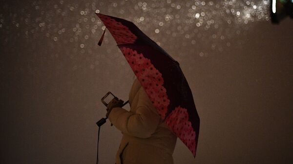 Женщина под зонтом идет по улице. Архивное фото - Sputnik Кыргызстан