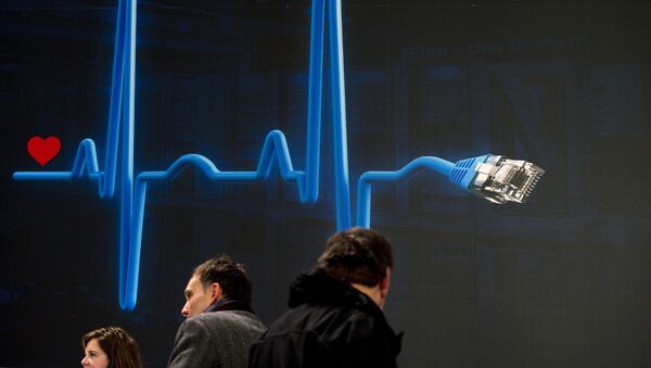 Посетители ярмарки IT технологий на фоне плаката в виде сердечного пульса из сетевого кабеля. - Sputnik Кыргызстан