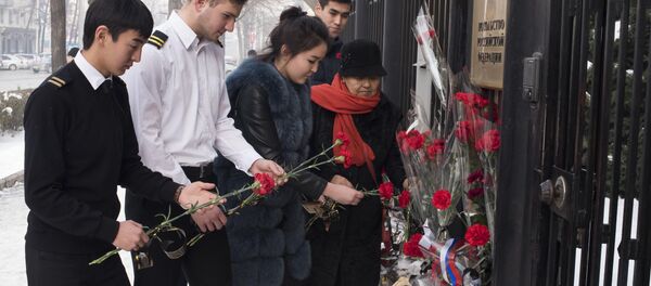 Кыргызстанцы несут цветы в посольство России в Бишкеке в память о погибших во время крушения самолета Минобороны РФ - Sputnik Кыргызстан