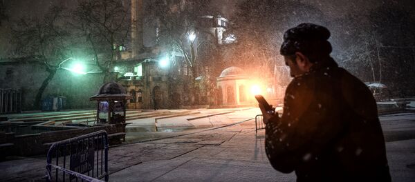 Прохожий с телефоном во время снегопада в турецком городе Стамбул - Sputnik Кыргызстан