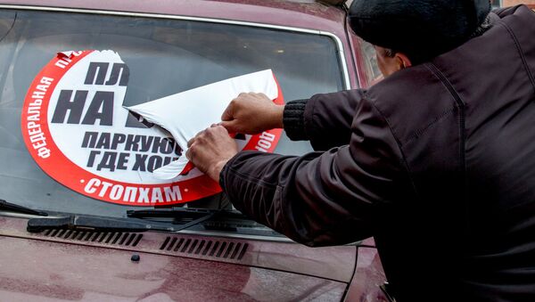 Мужчина снимает наклейку СтопХам с лобового стекла автомобиля. Архивное фото - Sputnik Кыргызстан