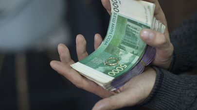 Мужчина держит деньги и обручальное кольцо