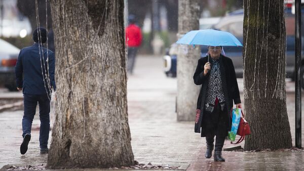 Женщина с зонтом идет по одной из улиц Бишкека во время дождя. Архивное фото - Sputnik Кыргызстан