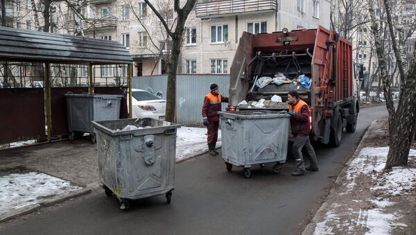 Сотрудники коммунальных служб выгружают мусор из контейнеров в мусоровоз. Архивное фото - Sputnik Кыргызстан