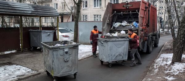 Сотрудники коммунальных служб выгружают мусор из контейнеров в мусоровоз. Архивное фото - Sputnik Кыргызстан