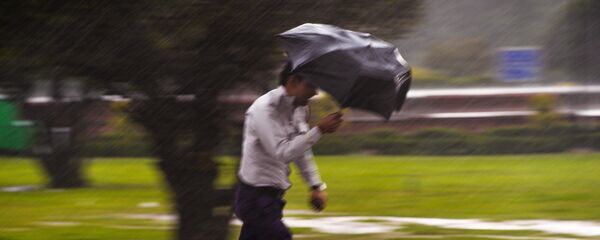 Мужчина с зонтом во время сильного дождя - Sputnik Кыргызстан