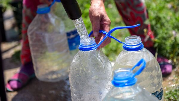 Человек набирает воду в бутылки. Архивное фото - Sputnik Кыргызстан