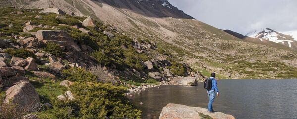 Путешественник у горного озера в Кыргызстане. Архивное фото Путешественник у горного озера в Кыргызстане. Архивное фото - Sputnik Кыргызстан