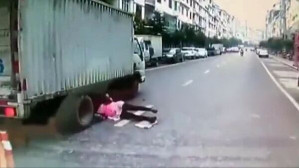 Женщина попала под колеса грузовика и чудом избежала смерти — видео из Китая - Sputnik Кыргызстан