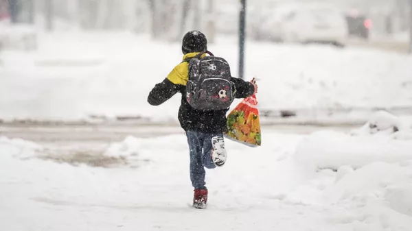 Школьник бежит по улице во время снегопада. Архивное фото  - Sputnik Кыргызстан