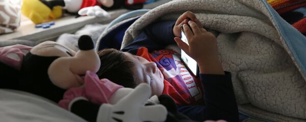Мальчик смотрит мультфильм на сотовом телефоне лежа в постели. Архивное фото Мальчик смотрит мультфильм на сотовом телефоне лежа в постели. Архивное фото - Sputnik Кыргызстан