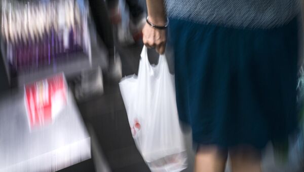 Женщина с полиэтиленовым пакетом в руке выходит из супермаркета. Архивное фото - Sputnik Кыргызстан