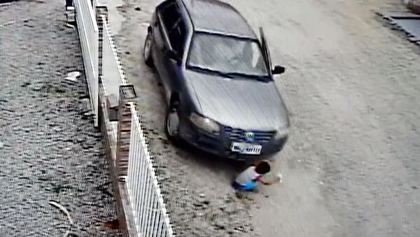 Ребенок чудом выжил, оказавшись под автомобилем, — видео из Бразилии - Sputnik Кыргызстан