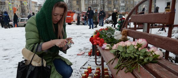 Женщина зажигает свечу возле здания торгового центра «Зимняя вишня» в Кемерово, где произошел пожар. Женщина зажигает свечу возле здания торгового центра «Зимняя вишня» в Кемерово, где произошел пожар. - Sputnik Кыргызстан