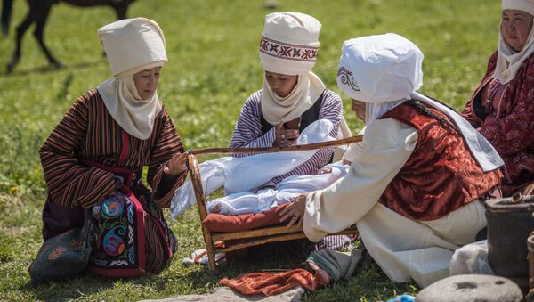 Женщины в национальных костюмах укладывают ребенка в колыбель. Архивное фото - Sputnik Кыргызстан