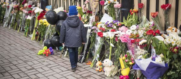 Ребенок у ворот посольства России в Бишкеке, где люди оставляют цветы и игрушки в память о погибших при пожаре в ТЦ в Кемерово. Архивное фото - Sputnik Кыргызстан