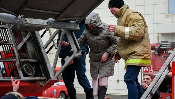 Сотрудники пожарной охраны МЧС помогают посетителям выбраться из торгового центра «Зимняя вишня» в Кемерово, где произошел пожар. - Sputnik Кыргызстан