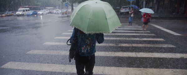 Девушка с зонтом переходит улиц во время сильного дождя. Архивное фото - Sputnik Кыргызстан