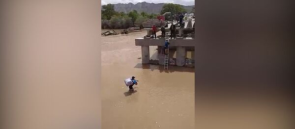 Мужчина с ребенком переходит вброд реку Нарын из-за недостроенного моста. Видео - Sputnik Кыргызстан