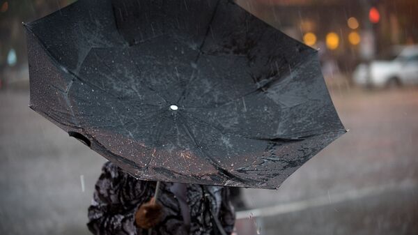 Женщина с зонтом во время сильного дождя с ветром. Архивное фото - Sputnik Кыргызстан