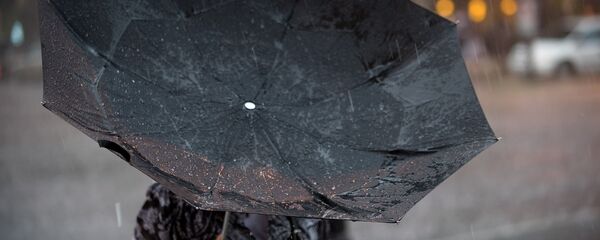 Женщина с зонтом во время сильного дождя с ветром. Архивное фото - Sputnik Кыргызстан