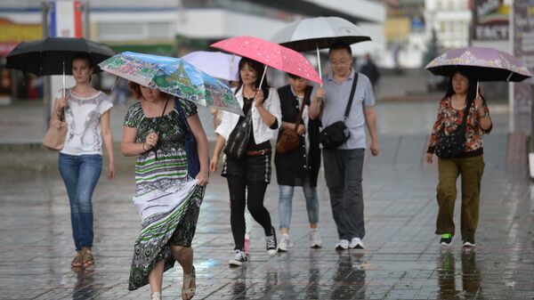 Прохожие идут по улице во время сильного дождя. Архивное фото  - Sputnik Кыргызстан