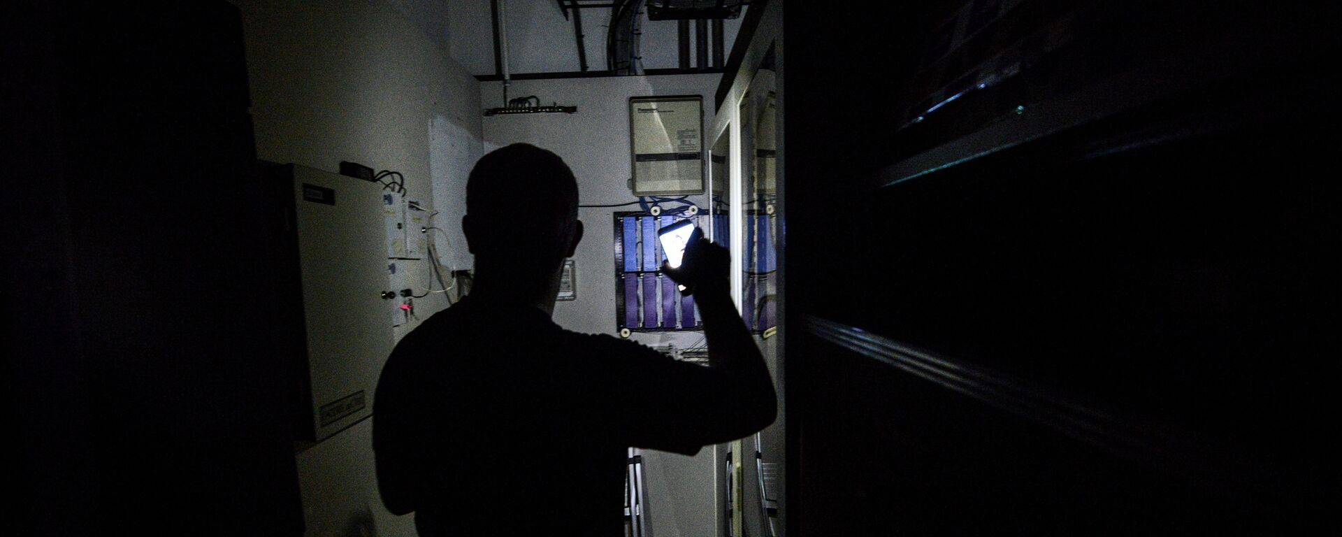 Мужчина с фонариком в руке проверяет электрощит. Архивное фото - Sputnik Кыргызстан, 1920, 30.08.2022