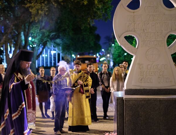 Священнослужитель читает молебен у импровизированного мемориала в Краснодаре в память о погибших при нападении на керченский колледж - Sputnik Кыргызстан