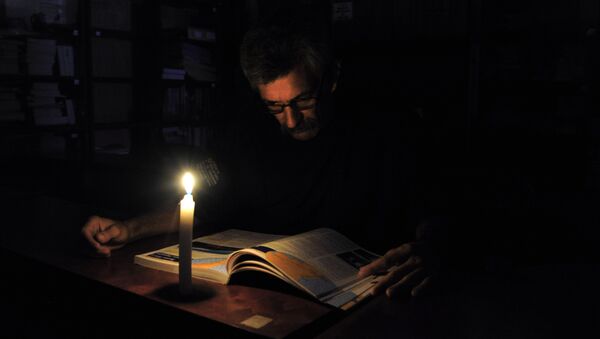 Человек читает со свечой во время отключения электроэнергии. Архивное фото - Sputnik Кыргызстан