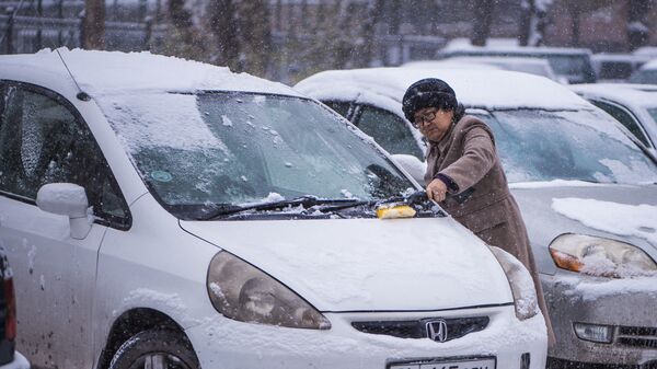 Женщина во время очистки автомобиля от снега в Бишкеке. Архивное фото - Sputnik Кыргызстан
