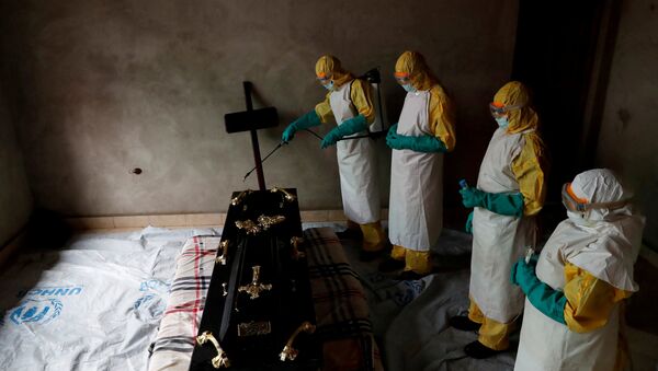 Медицинские работники дезинфицируют гроб, в котором находится тело человека умершего от вируса Эбола в Конго. Архивное фото - Sputnik Кыргызстан