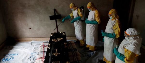 Медицинские работники дезинфицируют гроб, в котором находится тело человека умершего от вируса Эбола в Конго. Архивное фото - Sputnik Кыргызстан