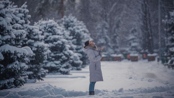 Девушка любуется снегопадом в одном из парков Бишкека. Архивное фото  - Sputnik Кыргызстан