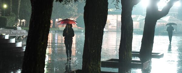 Жамгыр учуранда кол чатыр көтөргөн аял. Архив - Sputnik Кыргызстан