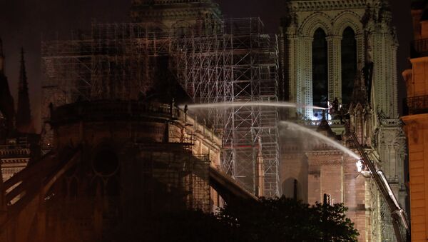 Пожарные во время тушения крупного пожара в здании собора Парижской Богоматери в Париже. 16 апреля 2019 года - Sputnik Кыргызстан