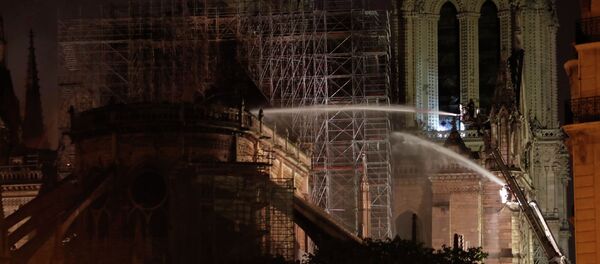 Пожарные во время тушения крупного пожара в здании собора Парижской Богоматери в Париже. 16 апреля 2019 года - Sputnik Кыргызстан