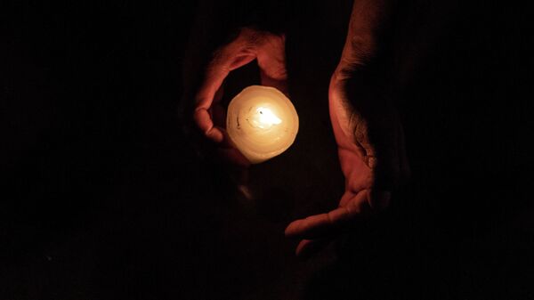 Человек с зажженой свечой в темноте. Архивное фото - Sputnik Кыргызстан