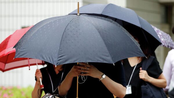 Женщины с зонтами идут по улице в Токио во время дождя. Архивное фото - Sputnik Кыргызстан
