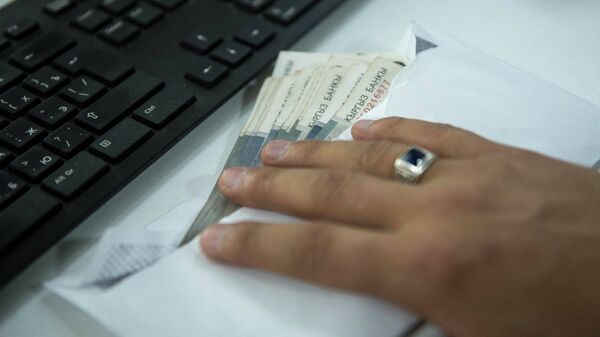 Мужчина держит конверт с деньгами на столе. Иллюстративное фото - Sputnik Кыргызстан