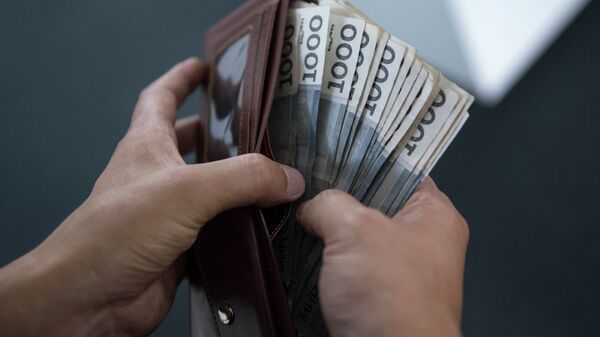 Мужчина вытаскивает деньги из кошелка. Архивное фото - Sputnik Кыргызстан