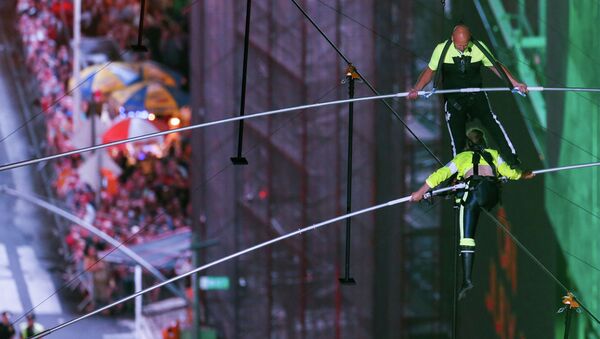 Американский канатоходец Ник Валленда и его сестра Лиджана проходят по канату, натянутому между небоскребами на высоте 25-го этажа над площадью Таймс-сквер в Нью-Йорке. 23 июня 2019 года - Sputnik Кыргызстан