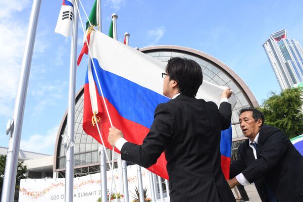 Вывешивание флага России у международного выставочного центра INTEX Osaka перед открытием саммита Группы двадцати в японской Осаке - Sputnik Кыргызстан