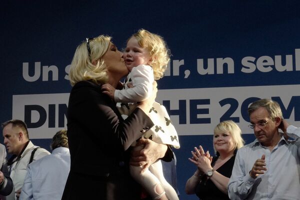 Марин ле Пен целует девочку во время предвыборного митинга в Энен-Бомоне, Франция - Sputnik Кыргызстан