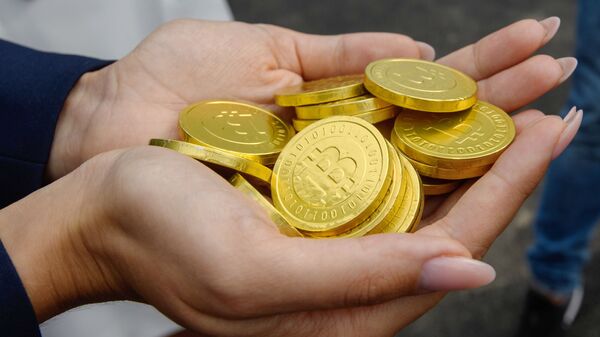 Девушка держит в ладонях символические монеты биткоина. Архивное фото - Sputnik Кыргызстан