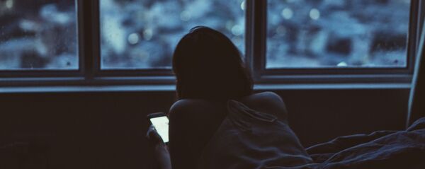 Девушка за смартфоном лежит в кровати. Архивное фото Девушка за смартфоном лежит в кровати. Архивное фото - Sputnik Кыргызстан